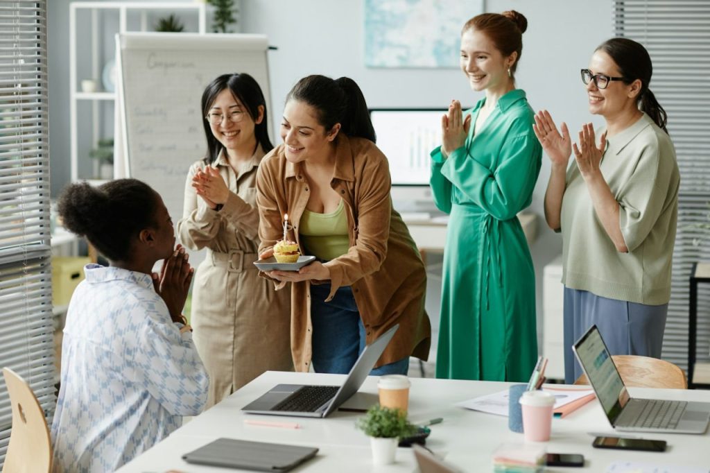 a group of women of diverse background, celebrating a colleague