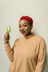 a happy woman in brown sweater smiling while holding an atm card