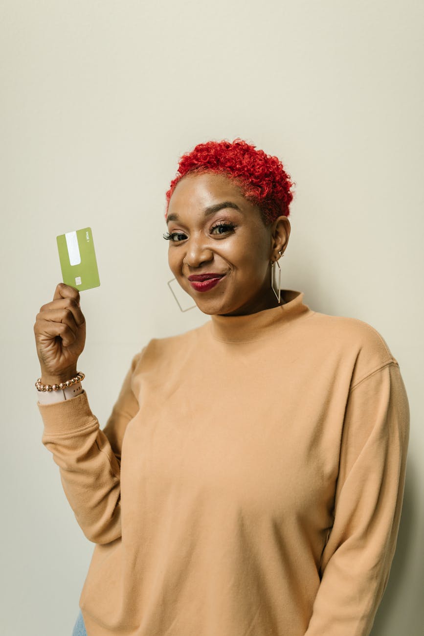 a happy woman in brown sweater smiling while holding an atm card